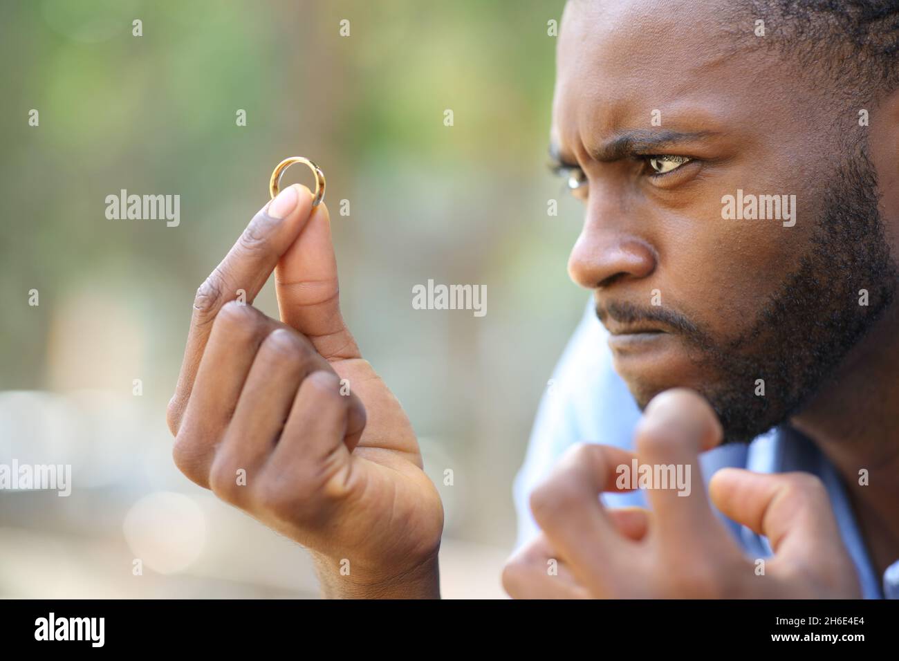 Homme en colère avec une peau noire regardant l'anneau de mariage Banque D'Images
