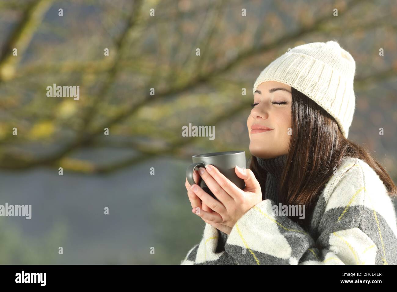 Une femme heureuse sent le café en hiver en plein air dans la montagne Banque D'Images