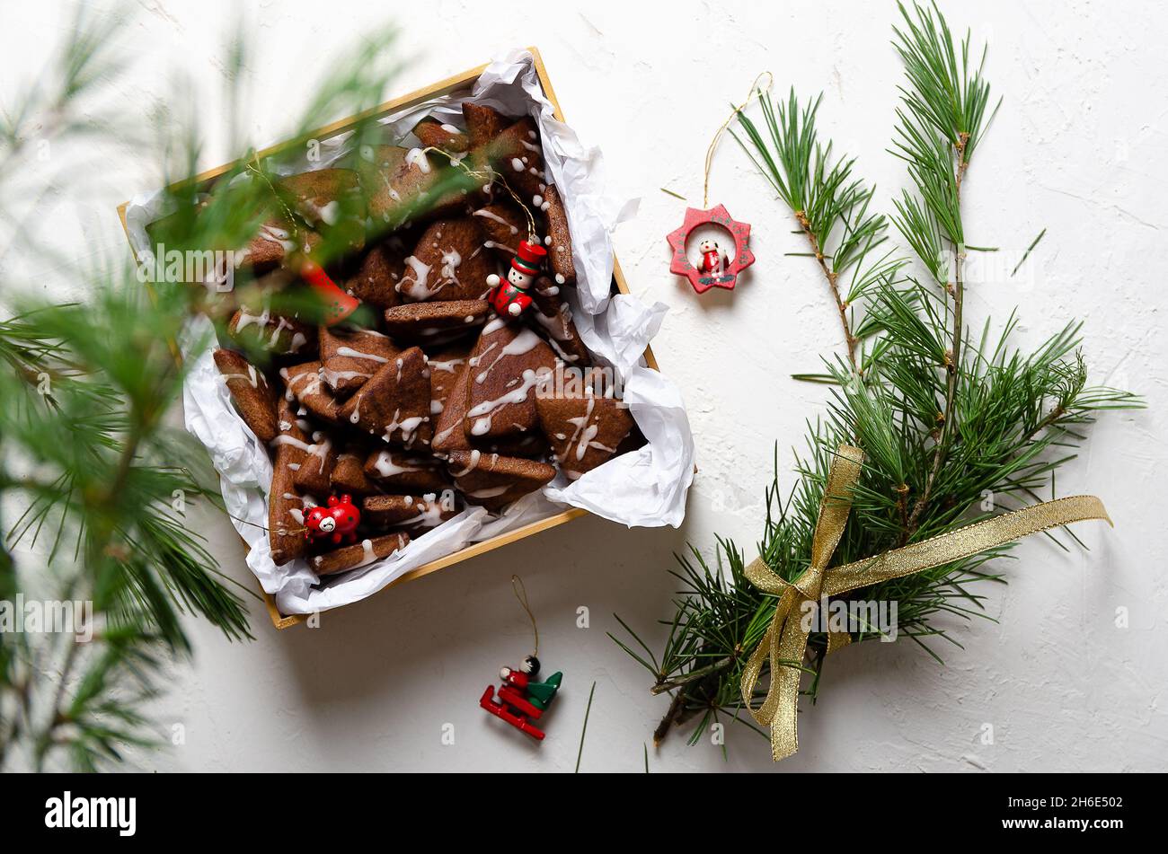 Biscuits au chocolat dans une boîte, branches de pin et jouets de Noël sur fond blanc. Banque D'Images