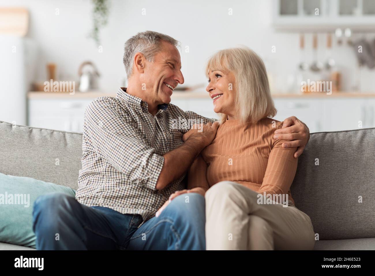 Gai mari mature embrassant la femme heureuse assise à la maison Banque D'Images