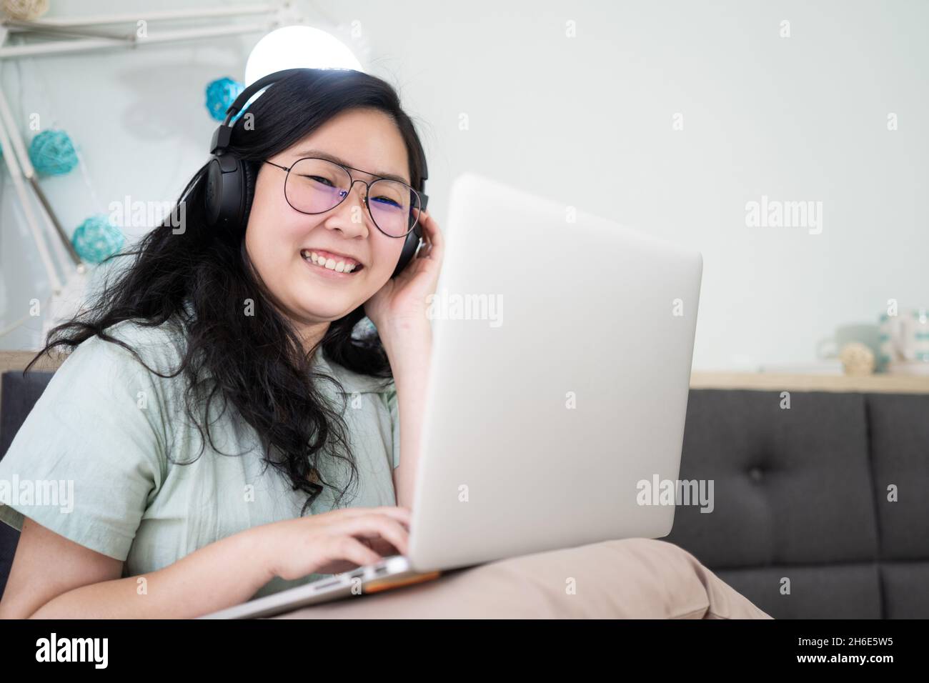 Lunettes belle femme asiatique travaille sur son ordinateur portable dans  la chambre à coucher avec un thème de couleur vert pastel - marron Photo  Stock - Alamy