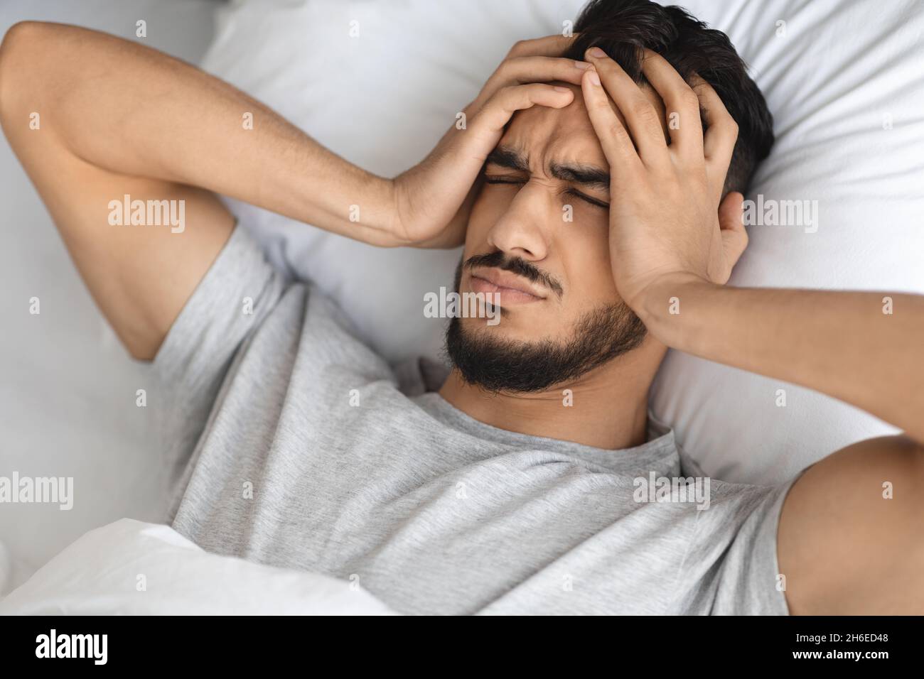 Concept de migraine.Jeune homme arabe se réveillant au lit avec des maux de  tête aigus Photo Stock - Alamy