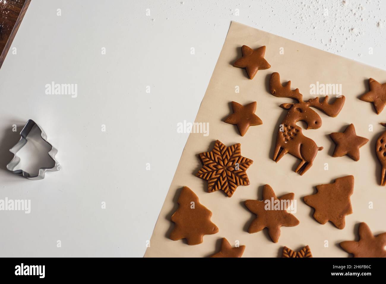 Motif de biscuits de pain d'épice de Noël sous forme d'animaux, d'arbres, de flocons de neige.Biscuits coupés de pâte crue sur un tapis de cuisson, vue de dessus, gros plan Banque D'Images