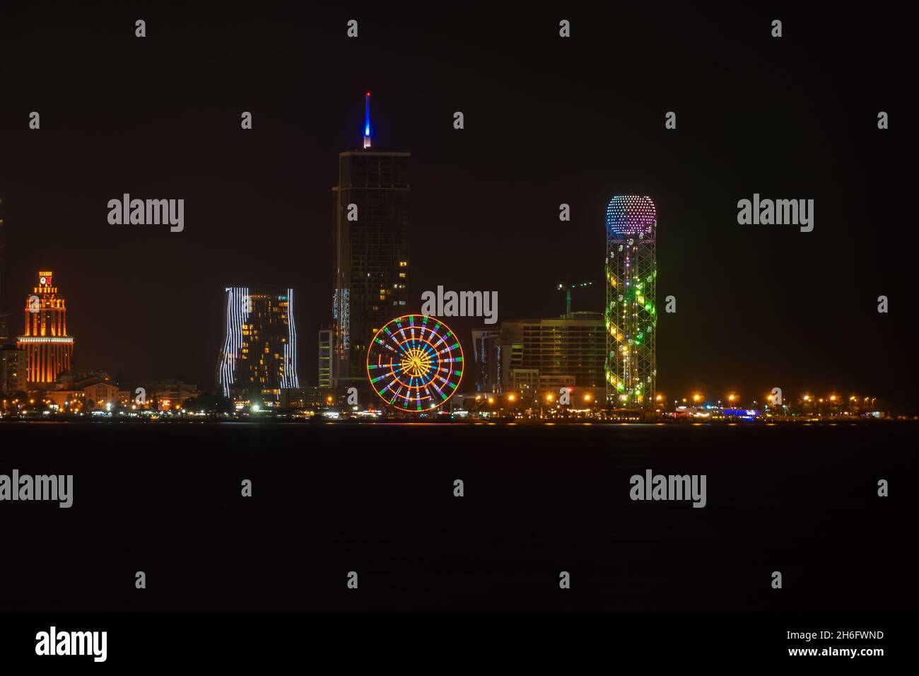 Vue depuis la mer jusqu'au remblai de Batumi par une nuit sombre.Illumination des bâtiments, des roues de Ferris, du remblai de Batumi, Adjara la nuit Banque D'Images