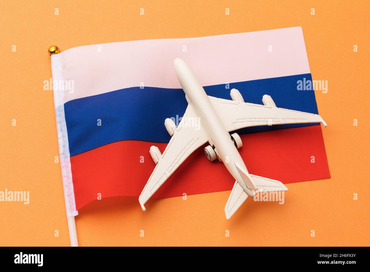Drapeau russe et avion jouet sur fond orange, concept sur le thème du voyage dans le pays Banque D'Images