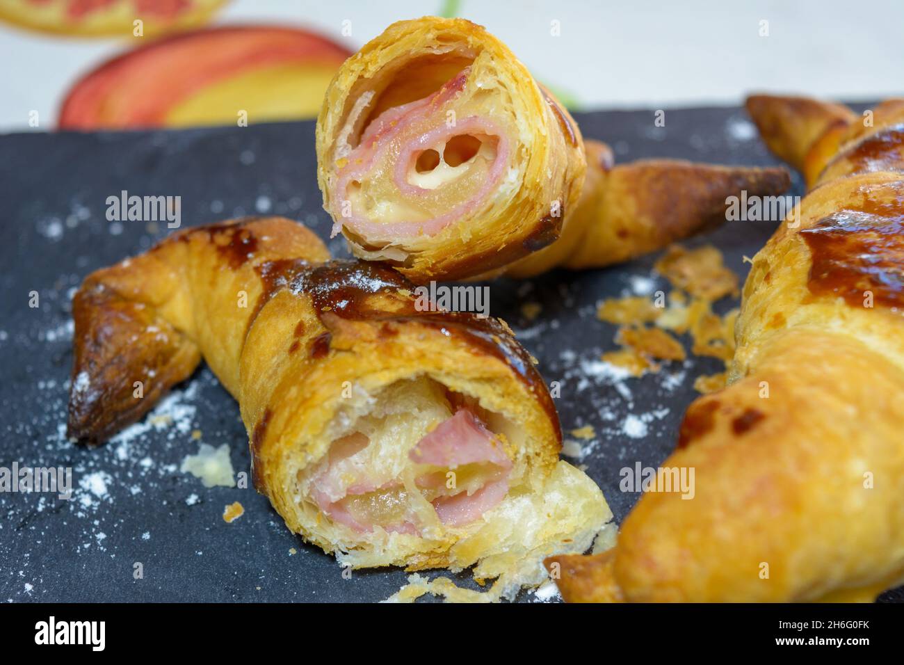 croissants frais farcis au jambon et au fromage fondu, prêts à manger, sur une assiette en ardoise grise Banque D'Images