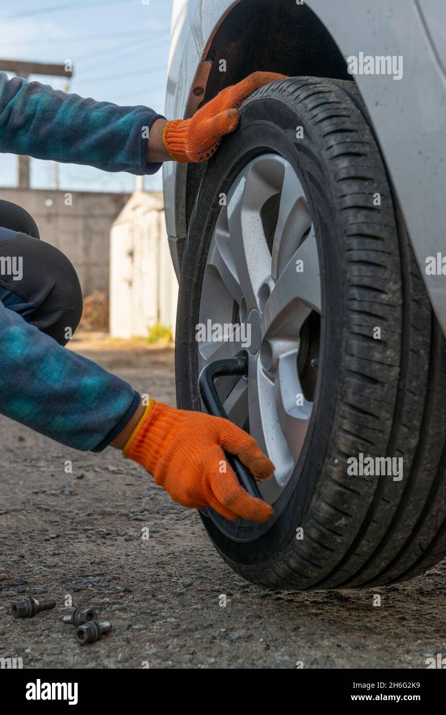 Remplacement des pneus de voiture.Photo verticale du conducteur avec une clé lors du remplacement d'un pneu crevé Banque D'Images