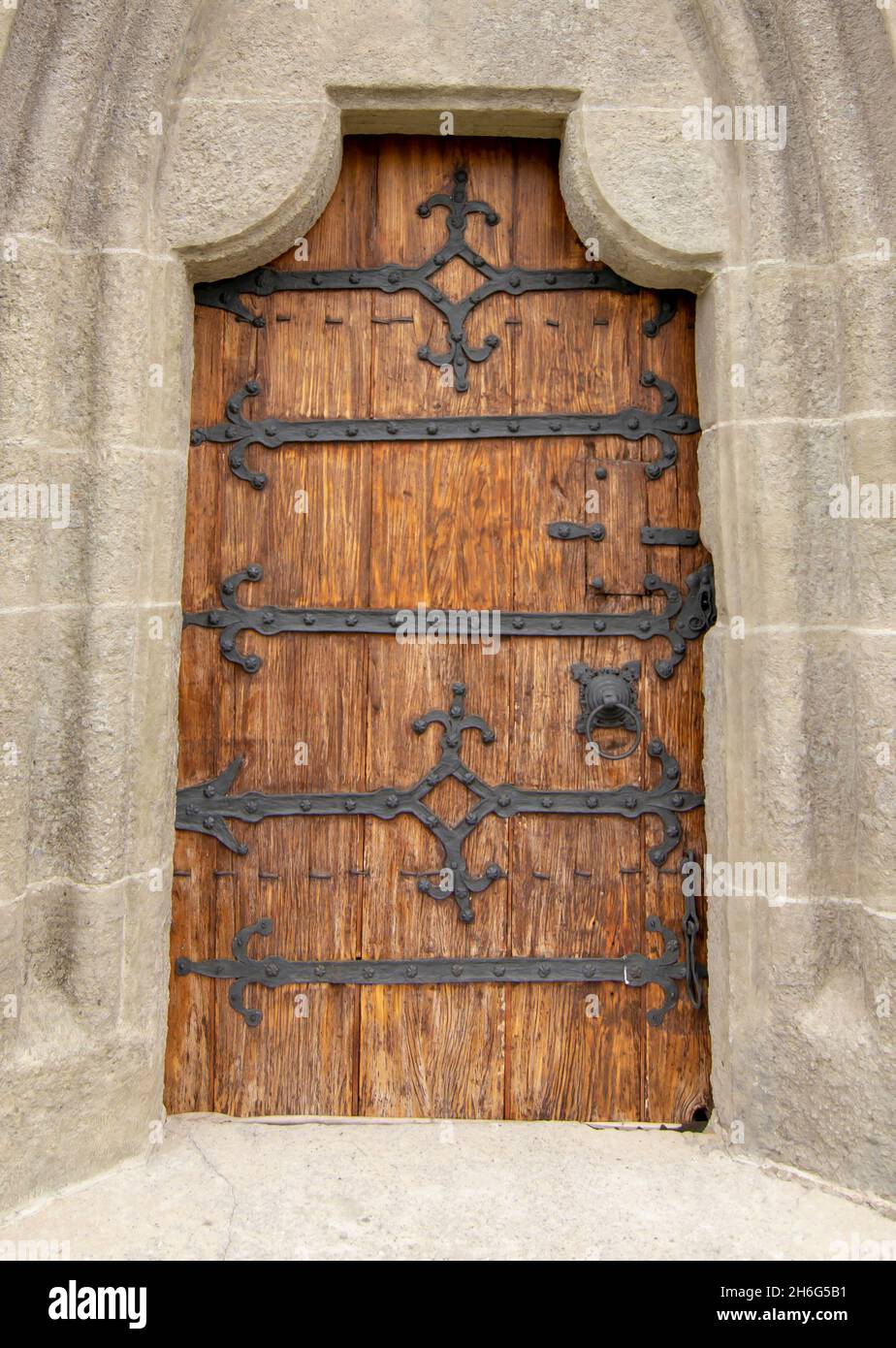 Ancienne église voûtée porte en bois avec ornements en fer noir dans un mur en pierre. Banque D'Images