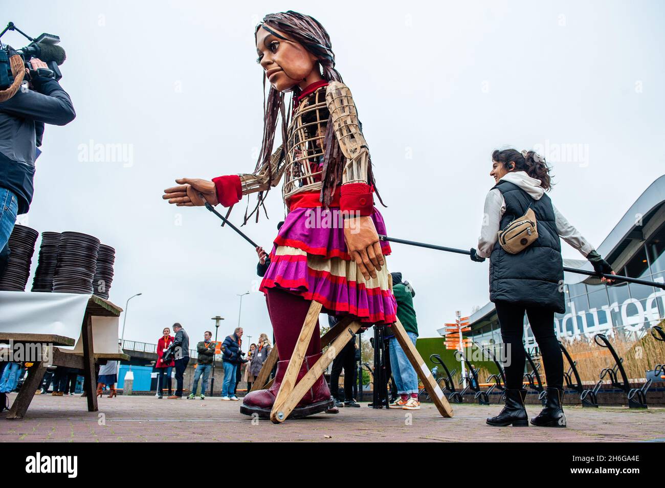 Little Amal arrive au parc.Amara, un nouveau centre culturel au centre de la Haye, a organisé dans le cadre de son « Open Festival », la visite de la marionnette géante « Little Amal », une jeune fille syrienne réfugiée de neuf ans et de plus de 11 mètres de hauteur jusqu'au parc miniature, Madurodam.Elle est invitée à participer au Festival en tant qu'invitée spéciale dans la ville pour attirer l'attention à travers l'Europe sur le sort des jeunes réfugiés qui ont fui la Syrie.Amal a été reçu à l'extérieur du parc par un groupe d'enfants, après qu'elle a pu se promener autour des répliques de modèle à l'échelle 1:25 de célèbres monuments hollandais, et dan Banque D'Images