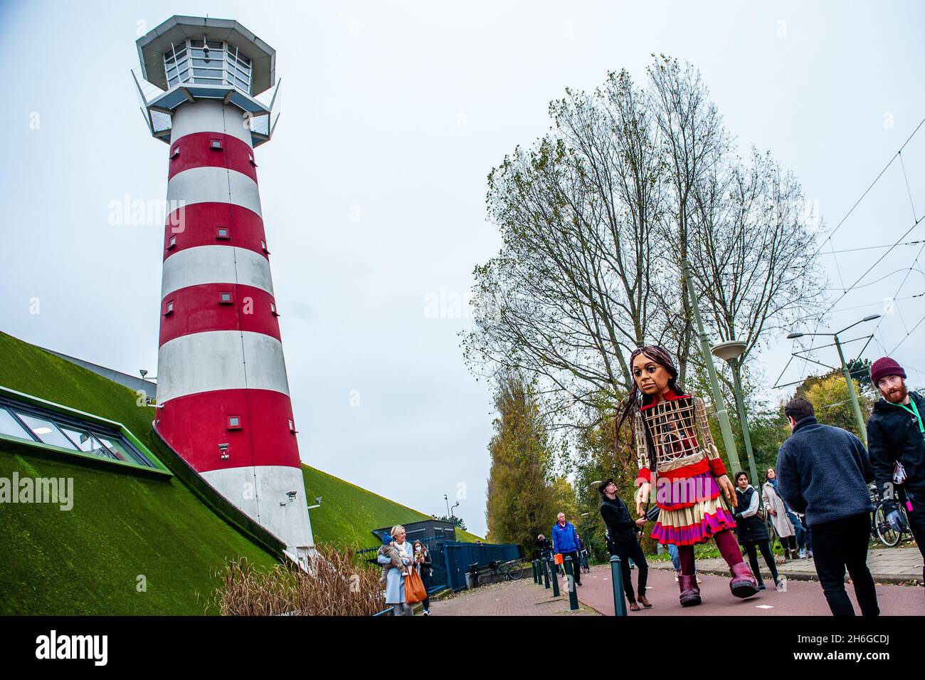 Little Amal arrive au parc.Amara, un nouveau centre culturel au centre de la Haye, a organisé dans le cadre de son « Open Festival », la visite de la marionnette géante « Little Amal », une jeune fille syrienne réfugiée de neuf ans et de plus de 11 mètres de hauteur jusqu'au parc miniature, Madurodam.Elle est invitée à participer au Festival en tant qu'invitée spéciale dans la ville pour attirer l'attention à travers l'Europe sur le sort des jeunes réfugiés qui ont fui la Syrie.Amal a été reçu à l'extérieur du parc par un groupe d'enfants, après qu'elle a pu se promener autour des répliques de modèle à l'échelle 1:25 de célèbres monuments hollandais, et dan Banque D'Images