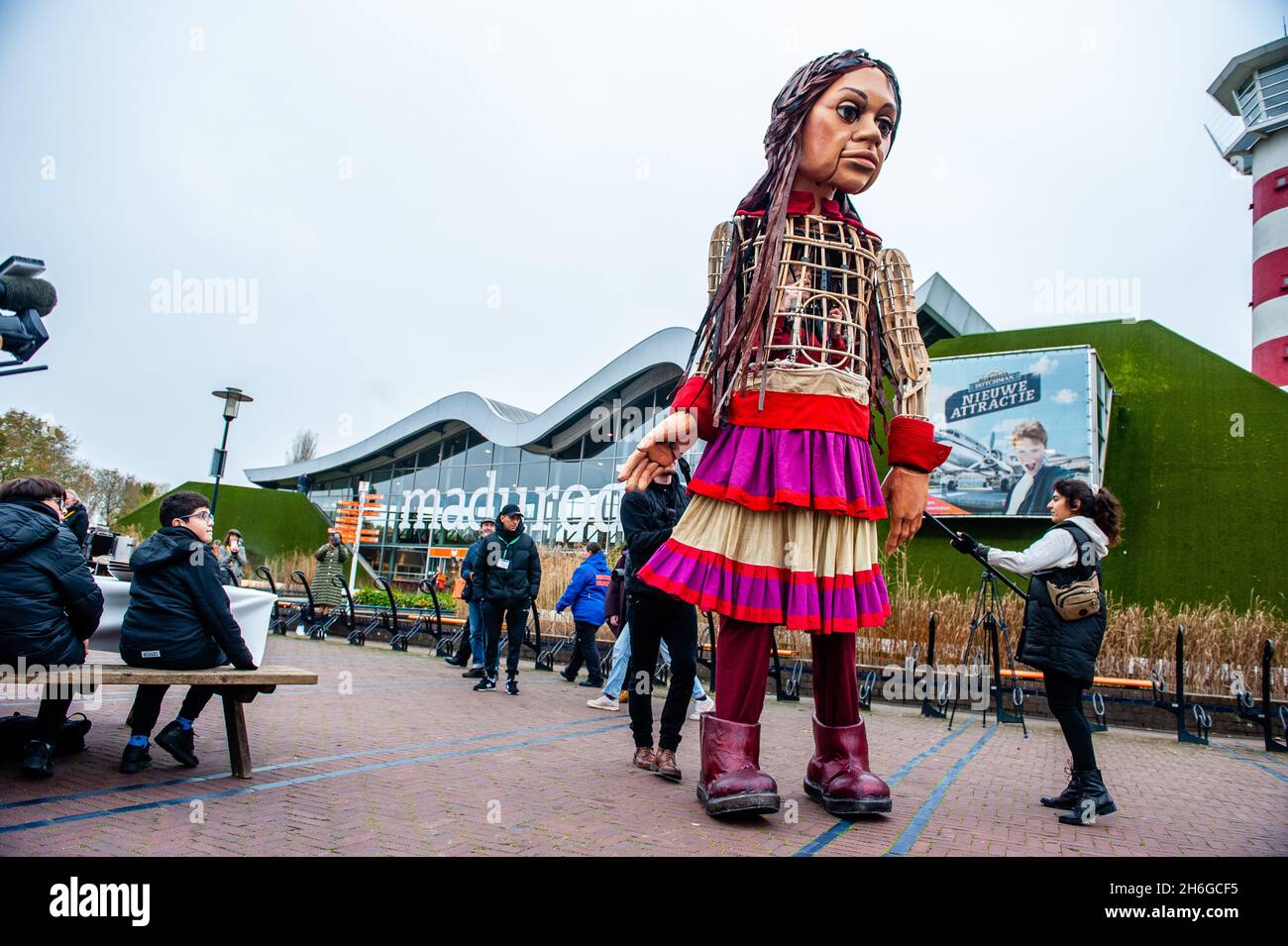 Little Amal arrive au parc.Amara, un nouveau centre culturel au centre de la Haye, a organisé dans le cadre de son « Open Festival », la visite de la marionnette géante « Little Amal », une jeune fille syrienne réfugiée de neuf ans et de plus de 11 mètres de hauteur jusqu'au parc miniature, Madurodam.Elle est invitée à participer au Festival en tant qu'invitée spéciale dans la ville pour attirer l'attention à travers l'Europe sur le sort des jeunes réfugiés qui ont fui la Syrie.Amal a été reçu à l'extérieur du parc par un groupe d'enfants, après qu'elle a pu se promener autour des répliques de modèle à l'échelle 1:25 de célèbres monuments hollandais, et dan Banque D'Images