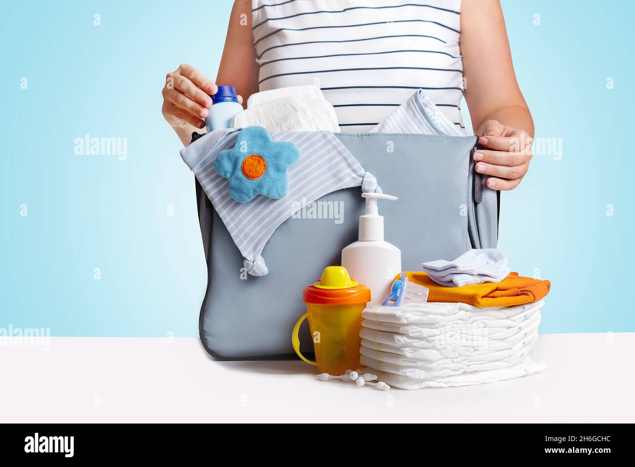 Femme emballage sac couches sur fond bleu. Banque D'Images