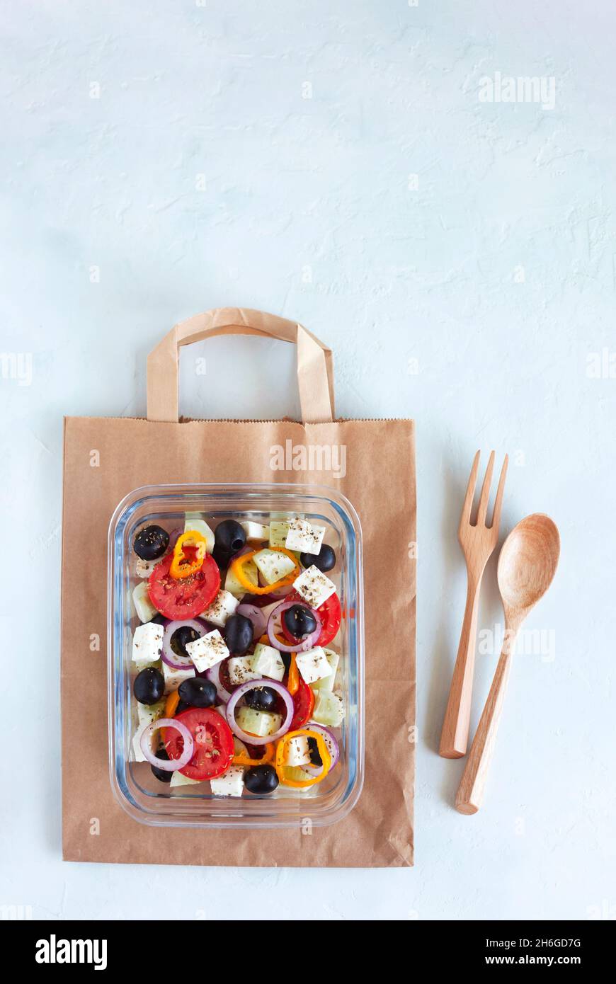 contenant avec salade grecque, coutellerie en bois, sur fond blanc, vue de dessus, espace de copie,concept de nourriture saine et zéro gaspillage Banque D'Images