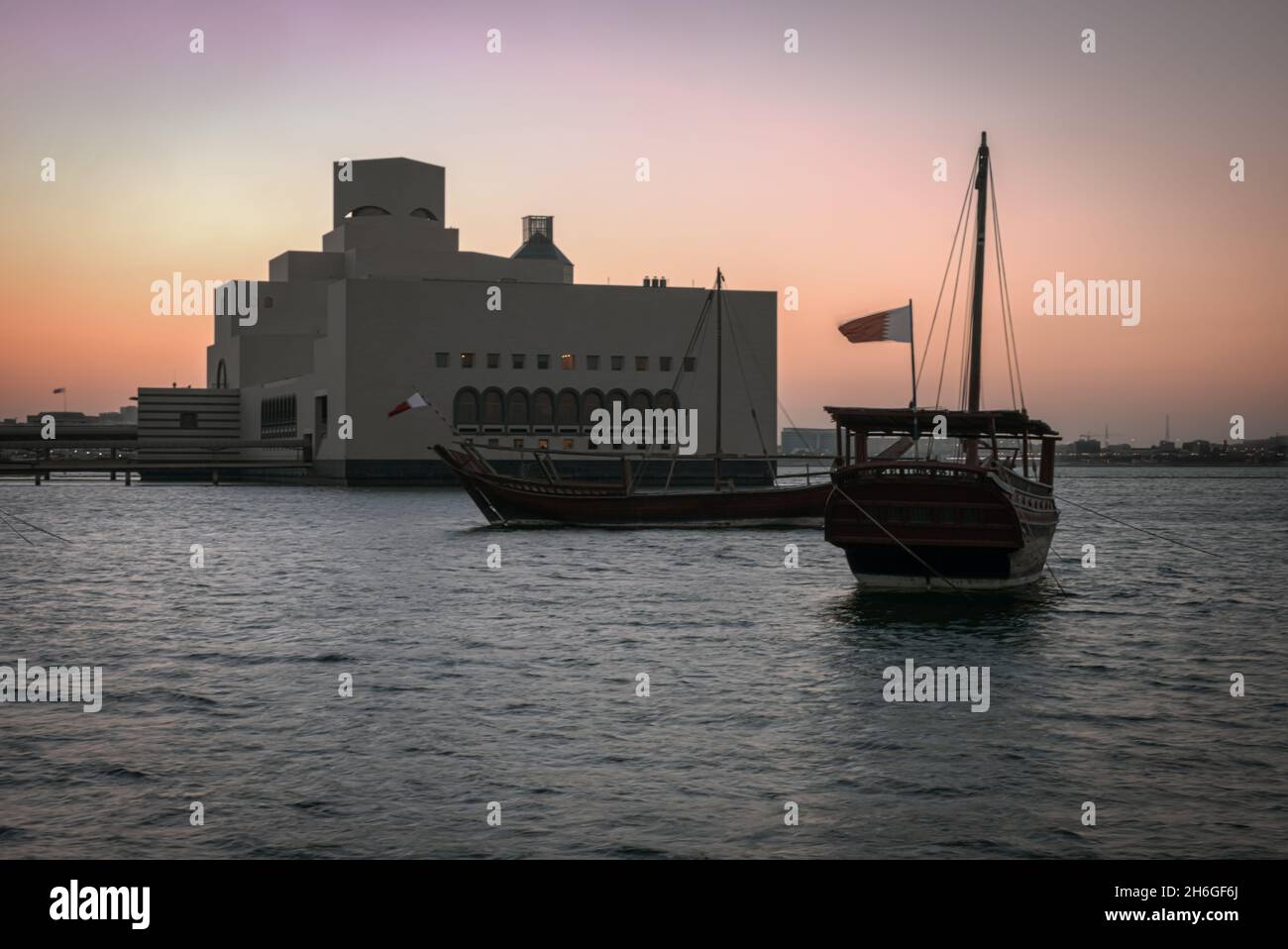 Musée d'art islamique à Doha, Qatar vue extérieure du coucher du soleil montrant l'architecture unique du musée avec des huws dans le golfe arabe en premier plan Banque D'Images