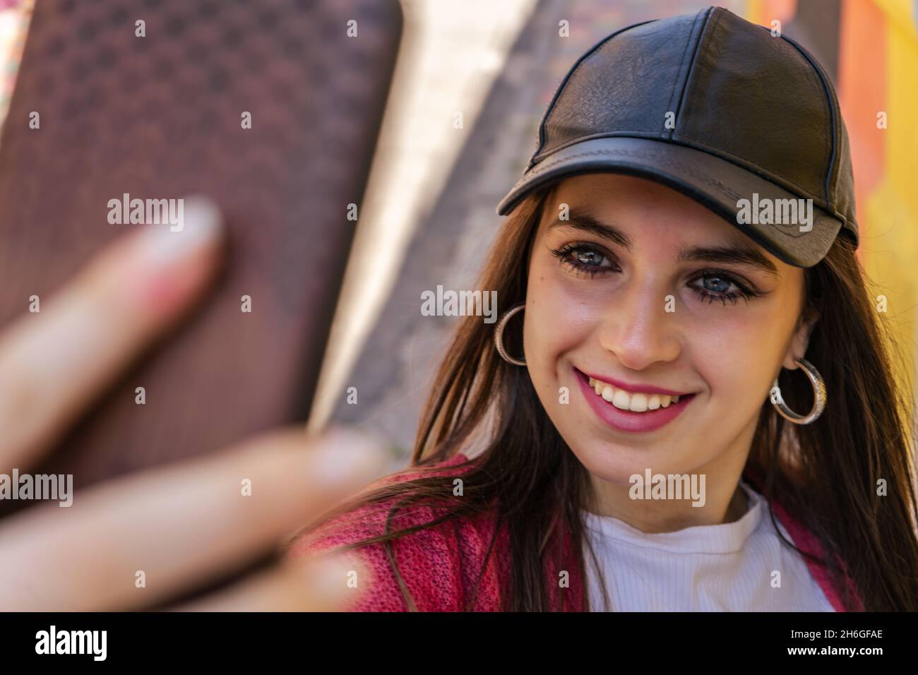 Portrait en gros plan d'une jeune femme attrayante tenant un smartphone appareil photo numérique avec ses mains et prendre un selfie autoportrait d'elle-même en se clin d'œil Banque D'Images