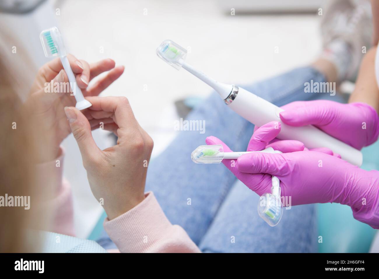 Femme méconnue examinant des têtes de rechange pour brosse à dents électrique au cabinet de dentiste Banque D'Images