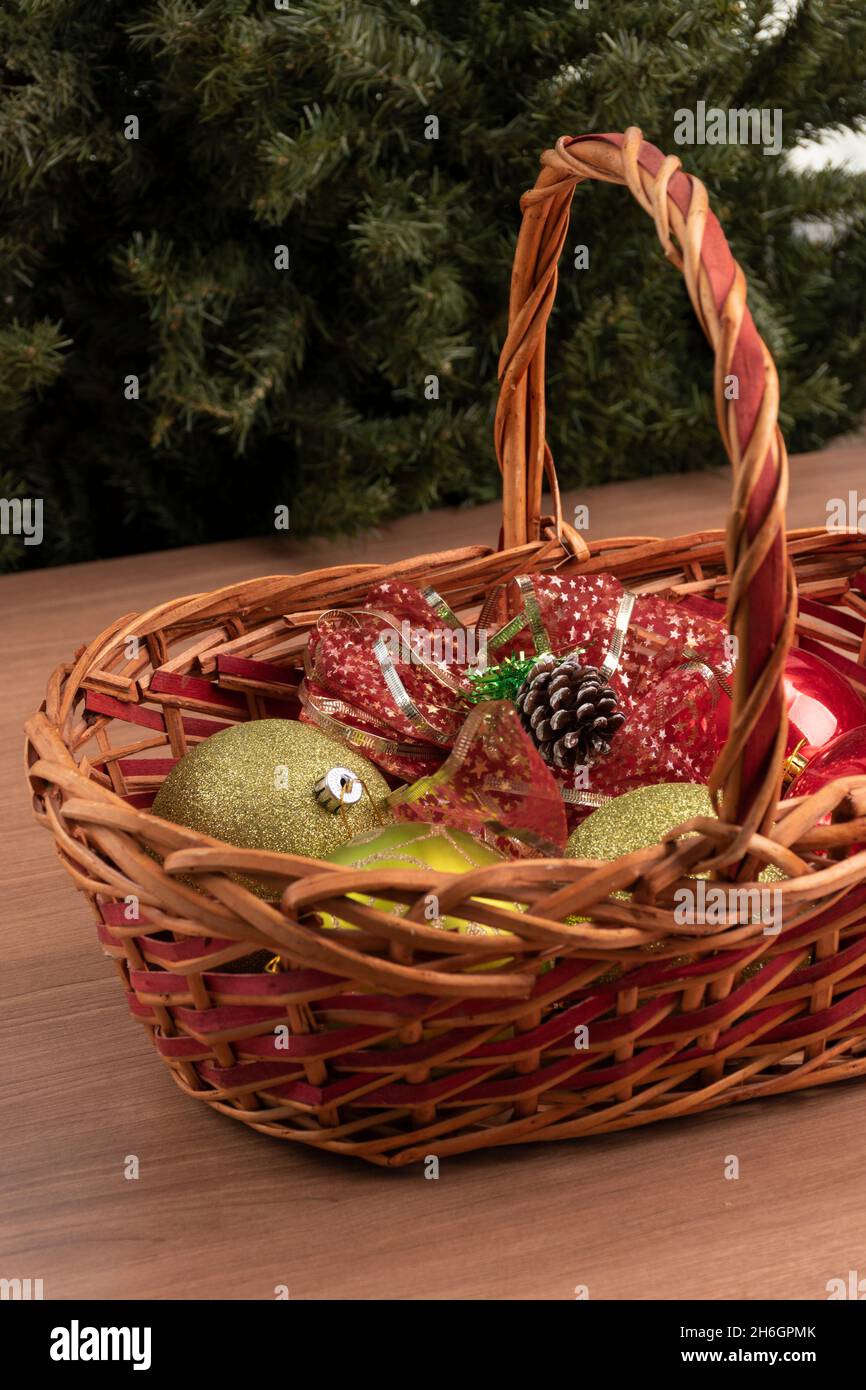 Panier en osier avec sphères vertes, quelques boules avec paillettes et ruban décoratif rouge, décorations de Noël en studio, beaux objets Banque D'Images