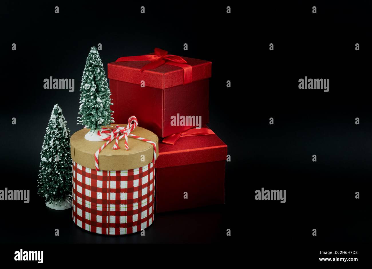 Boîtes-cadeaux avec décoration de Noël sur fond sombre.Boîtes cadeaux élégantes à chèques rouges et blancs.Photo d'arrière-plan noire, personne, espace de copie pour t Banque D'Images