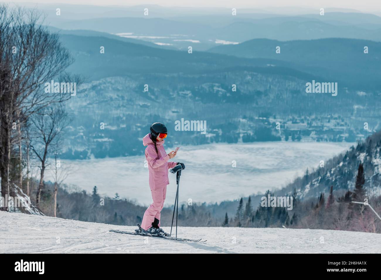 Téléphone en vacances de ski - femme skieuse utilisant l'application de téléphone sur la piste de ski dans un paysage naturel d'hiver étonnant.Fille regardant le port de smartphone mobile Banque D'Images