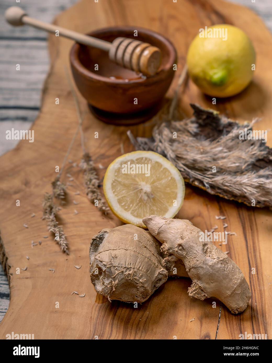 Composition de racines de gingembre, de citrons et de miel avec diffuseur de miel, sur une planche à découper en bois Banque D'Images