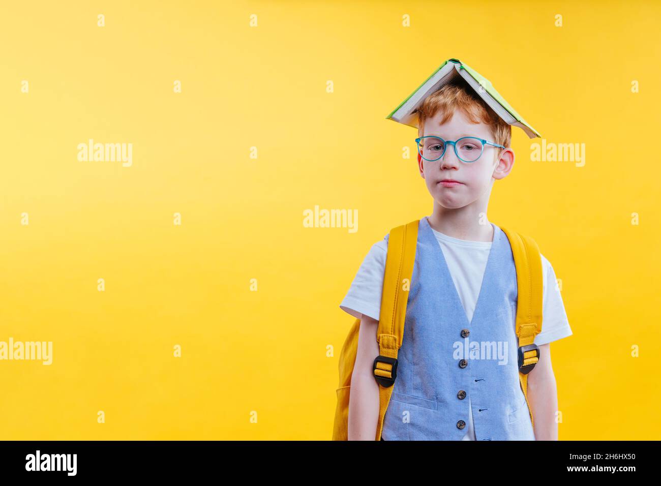Drôle de cheveux rouge élève-garçon avec des lunettes de vue sur fond jaune avec espace vide pour le texte Banque D'Images