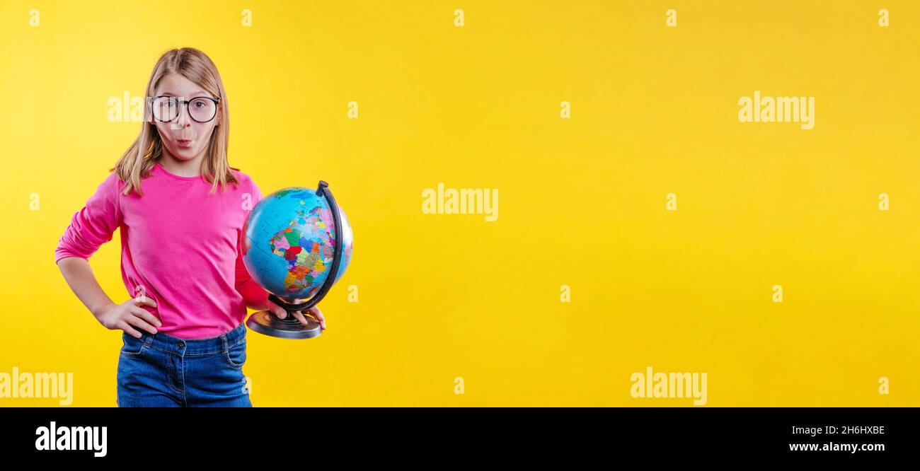 Surprise blonde cheveux école fille avec des lunettes de vue tenant le globe sur fond jaune avec espace vide pour le texte Banque D'Images