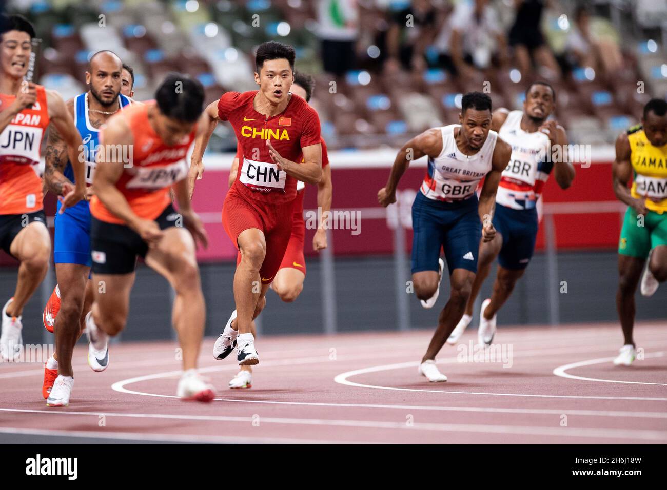 Les sprinters de la finale masculine de 4x100m dans les Jeux Olympiques de Tokyo 2020 effectuent un changement sur la courbe. Banque D'Images