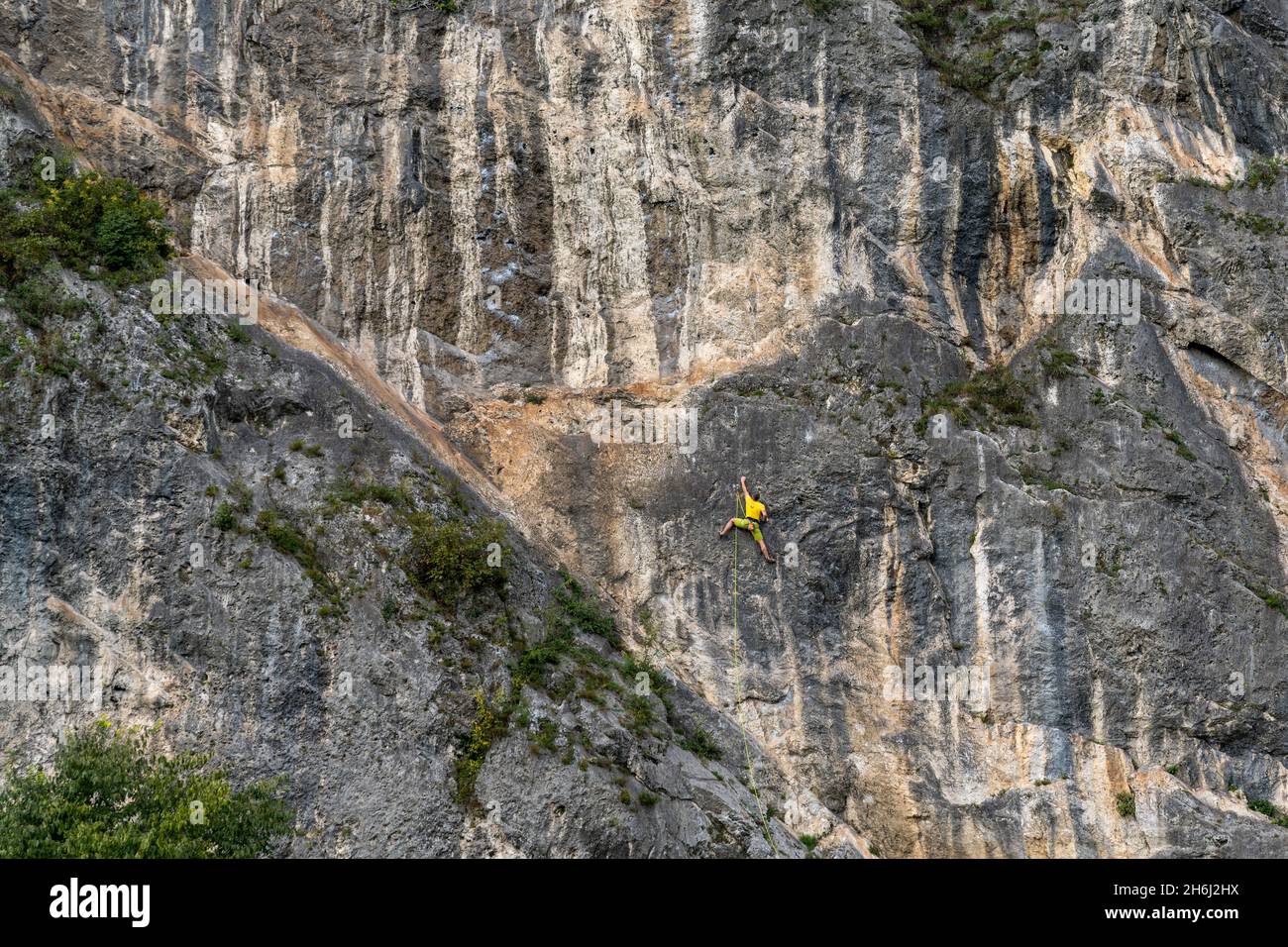 Esines, Italie - 12 octobre 2021 : grimpeur de roche vêtu d'un jaune vif, montant d'une pente verticale difficile dans les Alpes italiennes de Lomb Banque D'Images