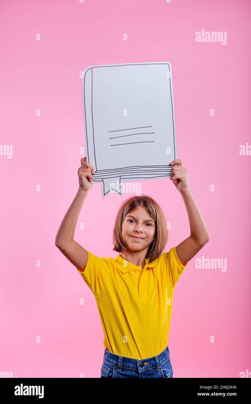 Petite fille tenant un livre de croquis en papier sur fond rose avec espace vide pour le texte.Concept d'idée. Banque D'Images