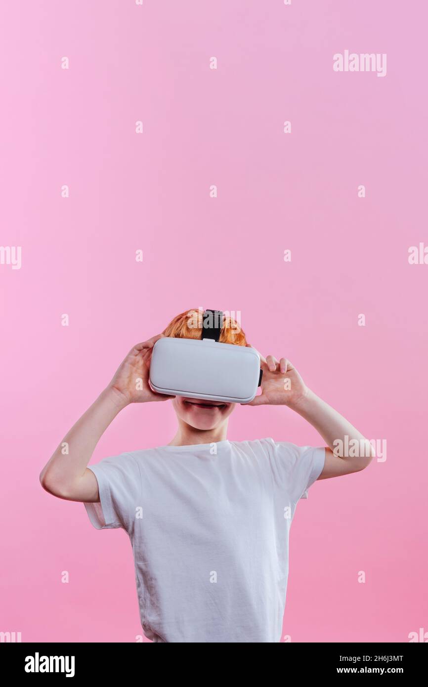 Adolescent portant un appareil de réalité virtuelle.Portrait de studio sur fond rose avec espace vide pour le texte Banque D'Images