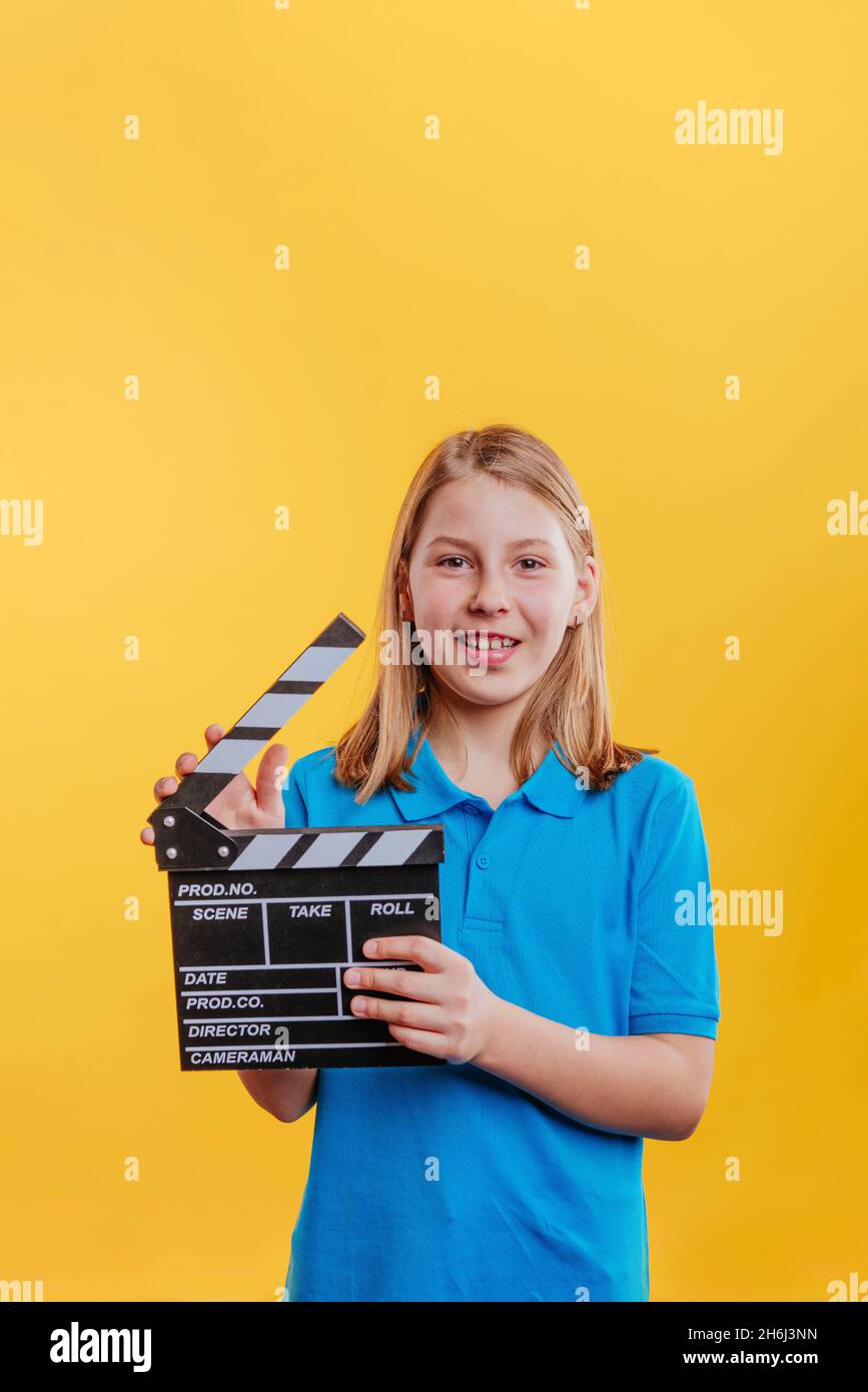Adolescente tenant un clapperboard moovie.Portrait de studio sur fond jaune avec espace vide pour le texte. Banque D'Images
