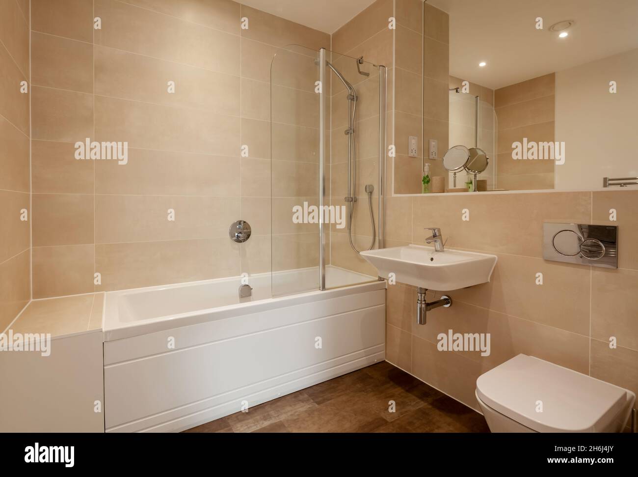 Cambridge, Angleterre - août 6 2019 : salle de bains/douche moderne partiellement carrelée avec lavabo en céramique mural, baignoire et grand miroir Banque D'Images