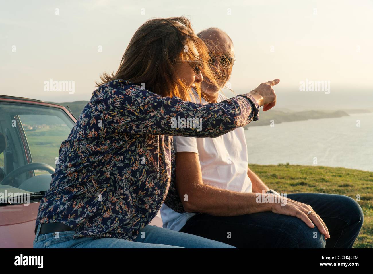 Couple âgé pointant vers l'océan et traversant la côte dans leur voiture décapotable 4x4 Banque D'Images