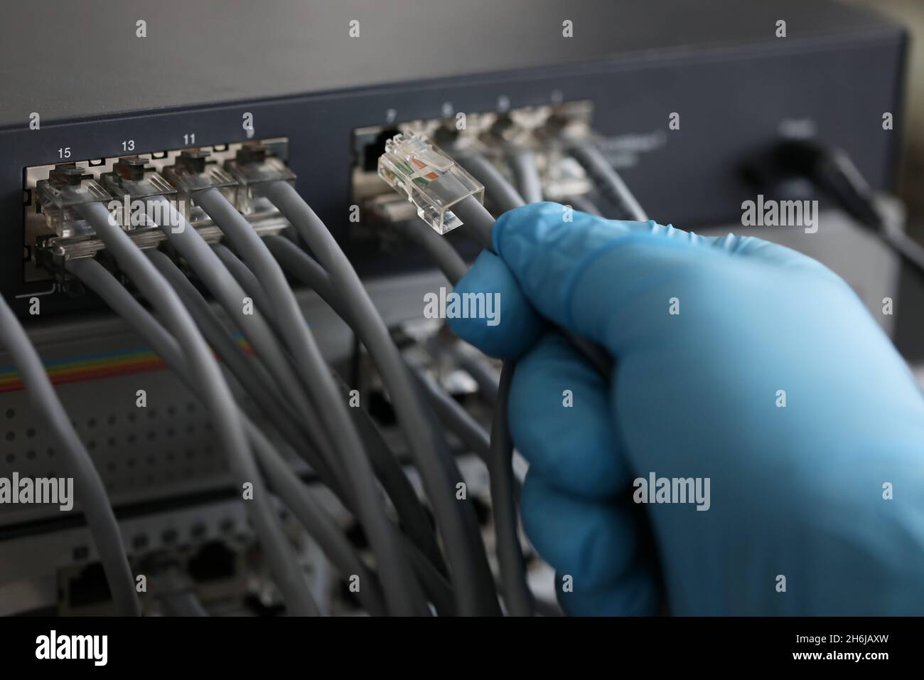 Personne travaillant dans une salle de serveurs réseau avec concentrateur fibre optique pour les communications numériques et Internet Banque D'Images