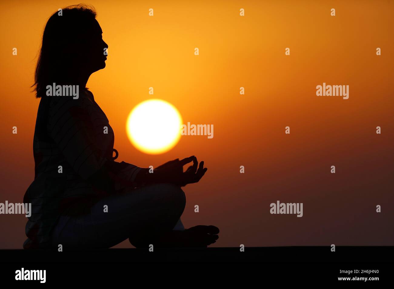 Femme pratiquant le yoga pose et la méditation au coucher du soleil comme concept de silence et de détente, Émirats arabes Unis, Moyen-Orient Banque D'Images