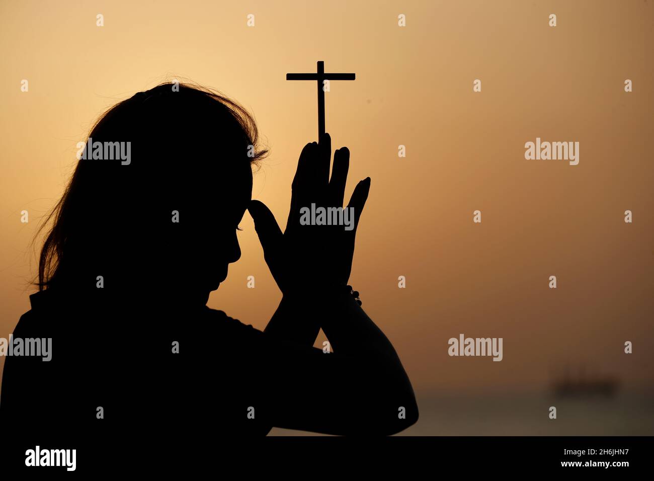 Silhouette de femme fidèle priant avec la croix chrétienne au coucher du soleil comme concept de religion, prière de foi nad, Dubaï, Émirats arabes Unis Banque D'Images