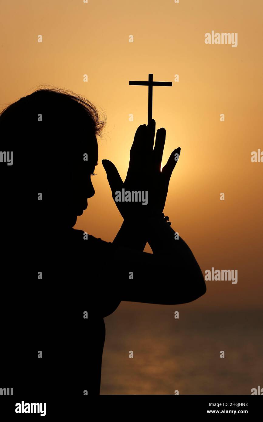 Silhouette de fidèle religieuse priant avec la croix chrétienne au coucher du soleil, Émirats arabes Unis, Moyen-Orient Banque D'Images