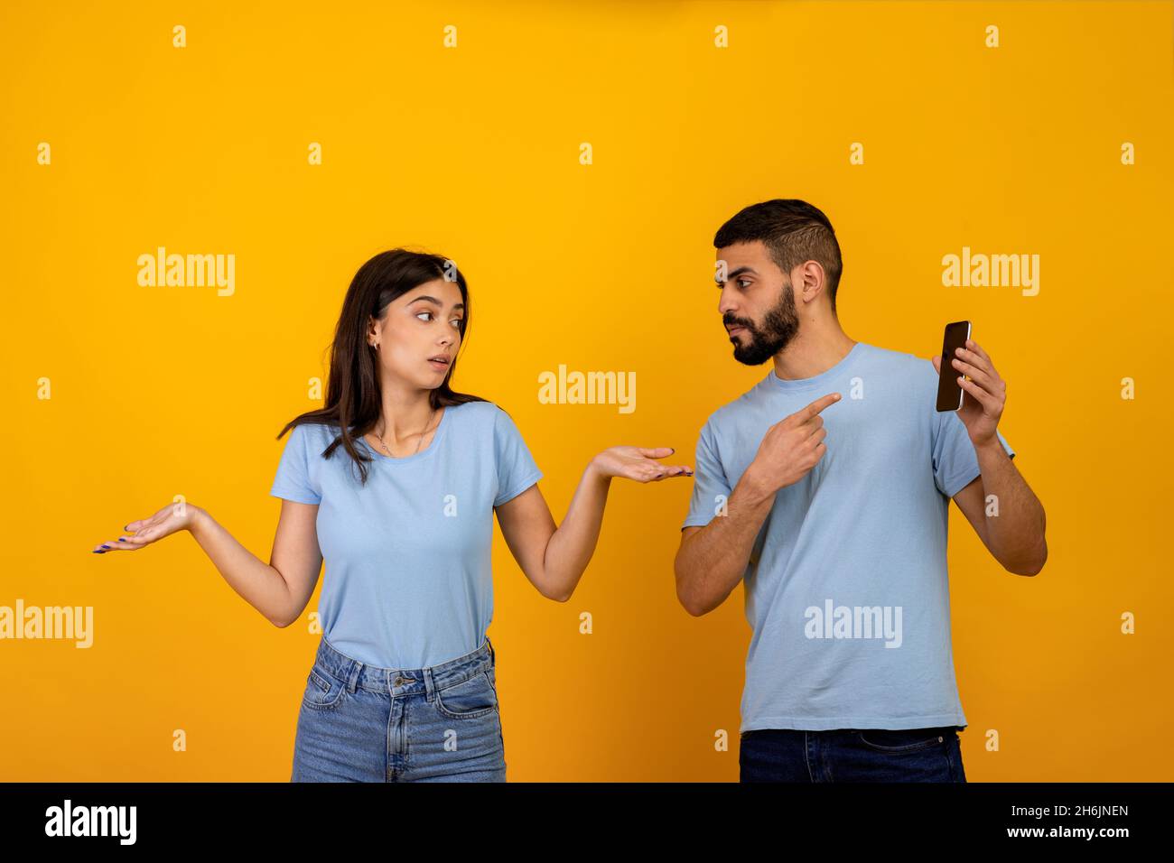 Une autre vie en ligne.Homme arabe en colère vérifiant son téléphone de petite amie, demandant à la femme d'expliquer, dame se propageant les mains Banque D'Images