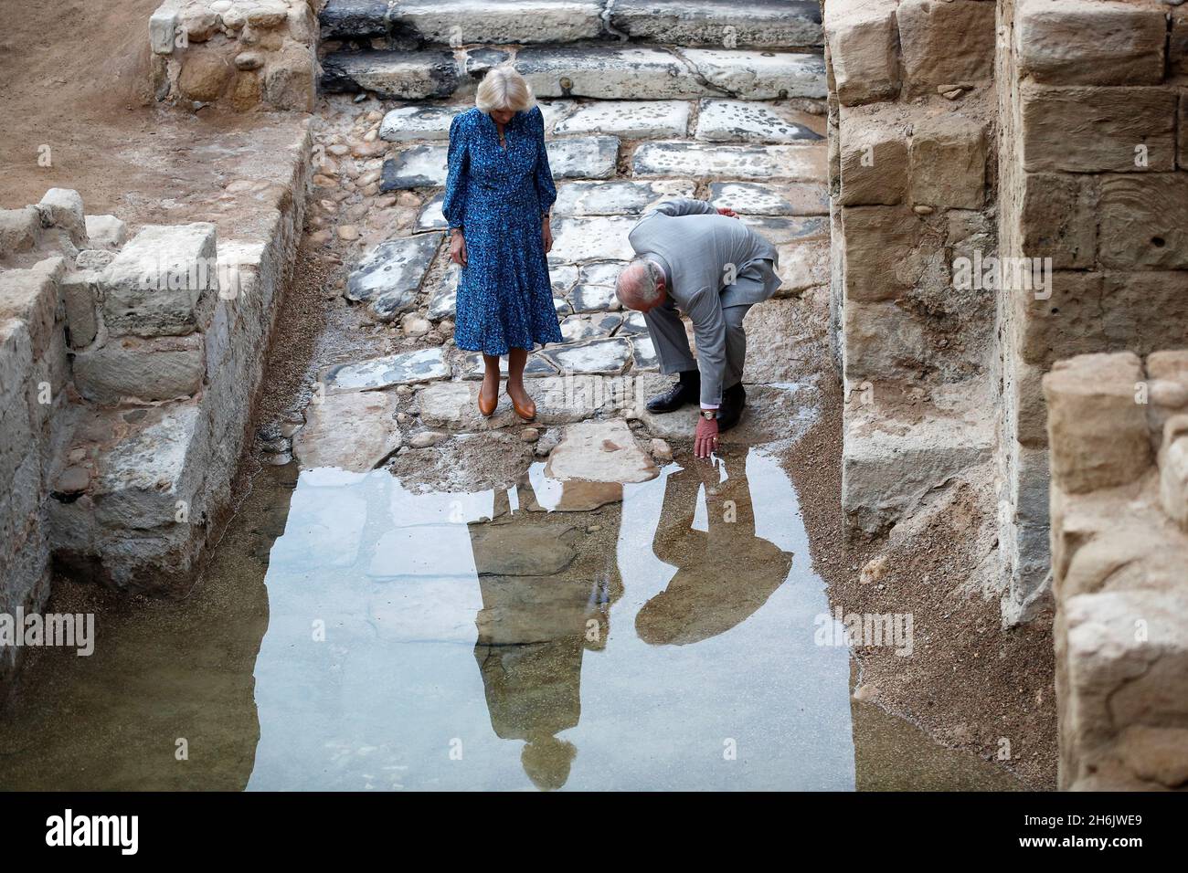 Le prince de Galles touche l'eau surveillée par la duchesse de Cornouailles lors d'une visite à la colline d'Élie et le site baptismal de Jésus-Christ à Juwafat al-Kafrayn en Jordanie le premier jour de leur visite au Moyen-Orient.Date de la photo: Mardi 16 novembre 2021. Banque D'Images
