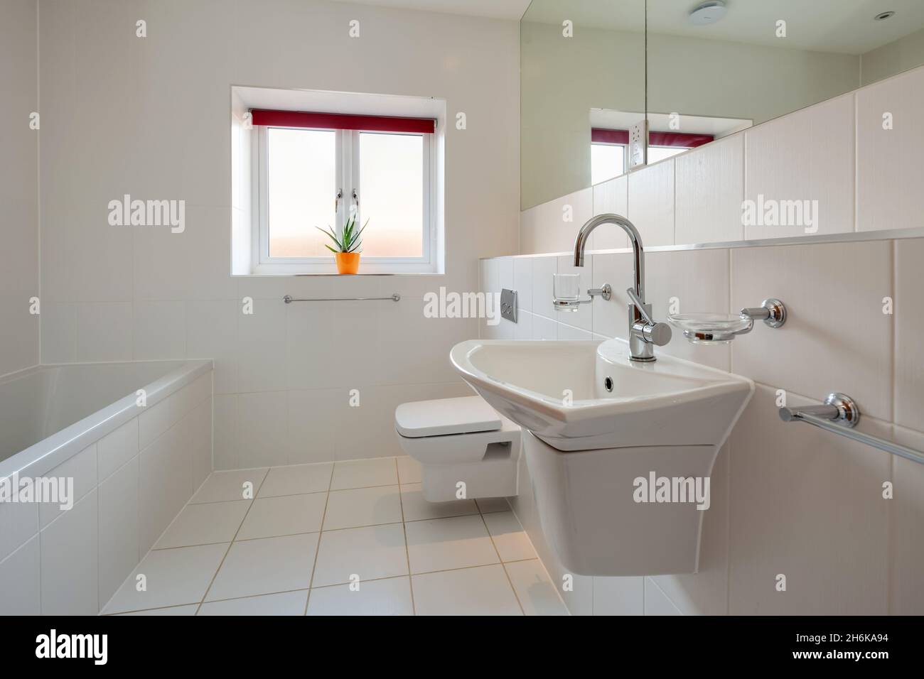 Essex, Angleterre - novembre 18 2019 : salle de bains entièrement carrelée blanche avec lavabo mural en céramique, baignoire et toilettes Banque D'Images