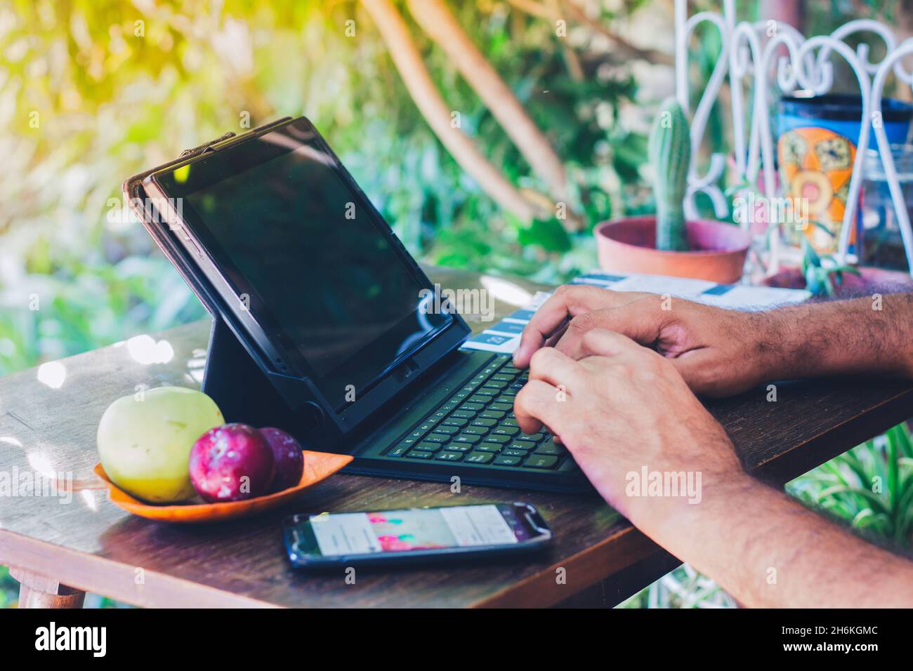 Homme utilisant son carnet à côté d'un fruit frais et téléphone portable sur une table en bois - travail de la maison Banque D'Images