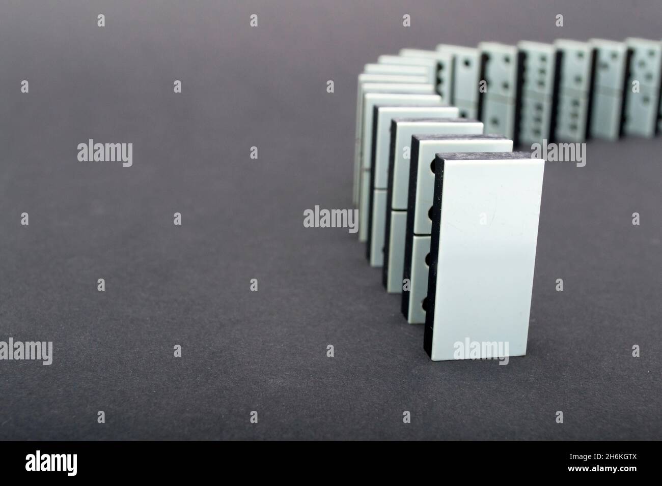 Dominos tombant en rangée, fond gris Banque D'Images