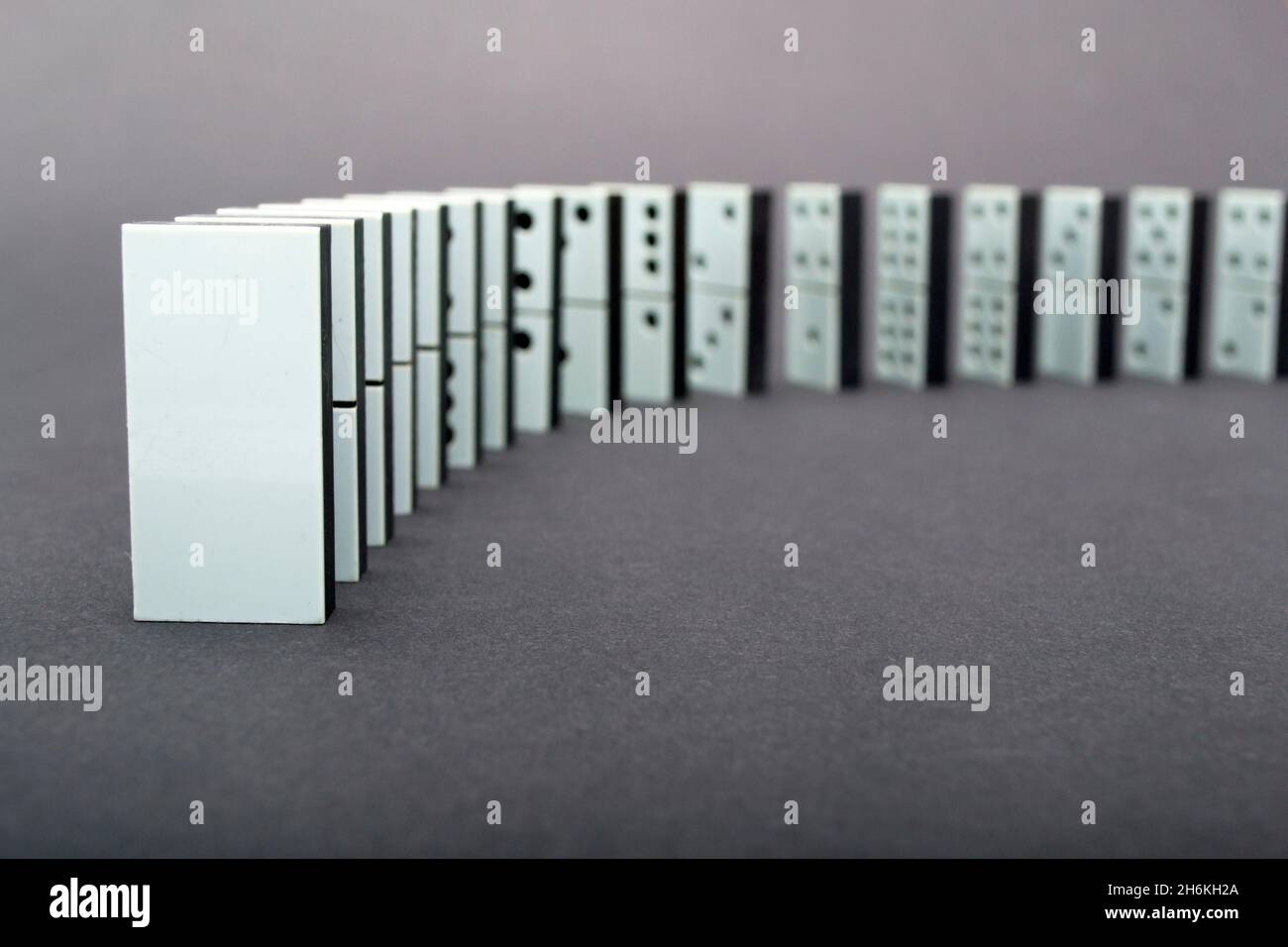 Dominos tombant en rangée, fond gris Banque D'Images