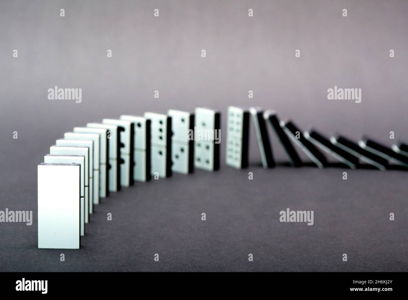 Dominos tombant en rangée, fond gris Banque D'Images