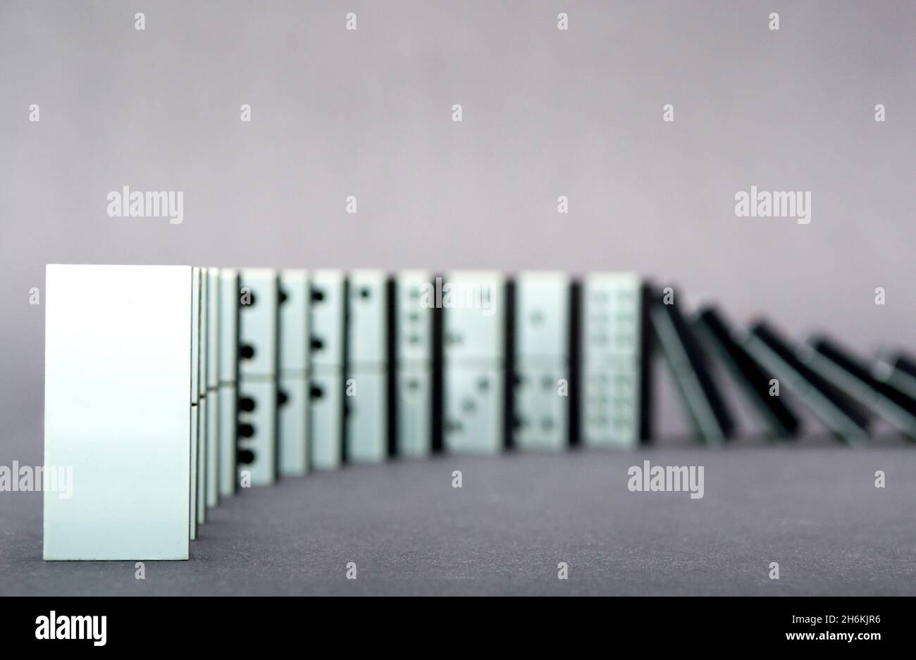 Dominos tombant en rangée, fond gris Banque D'Images
