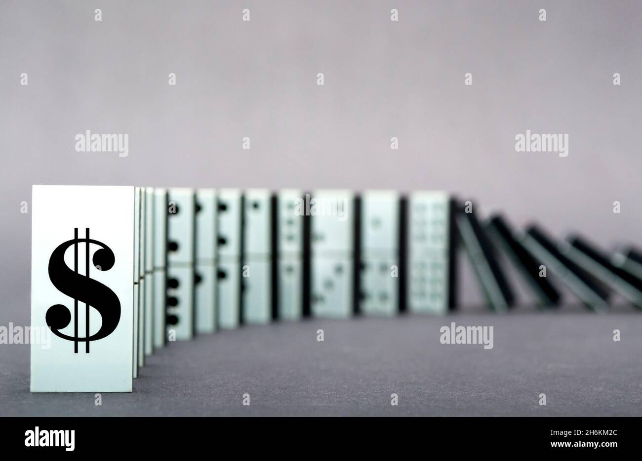 Dominos tombant en rangée, fond gris Banque D'Images