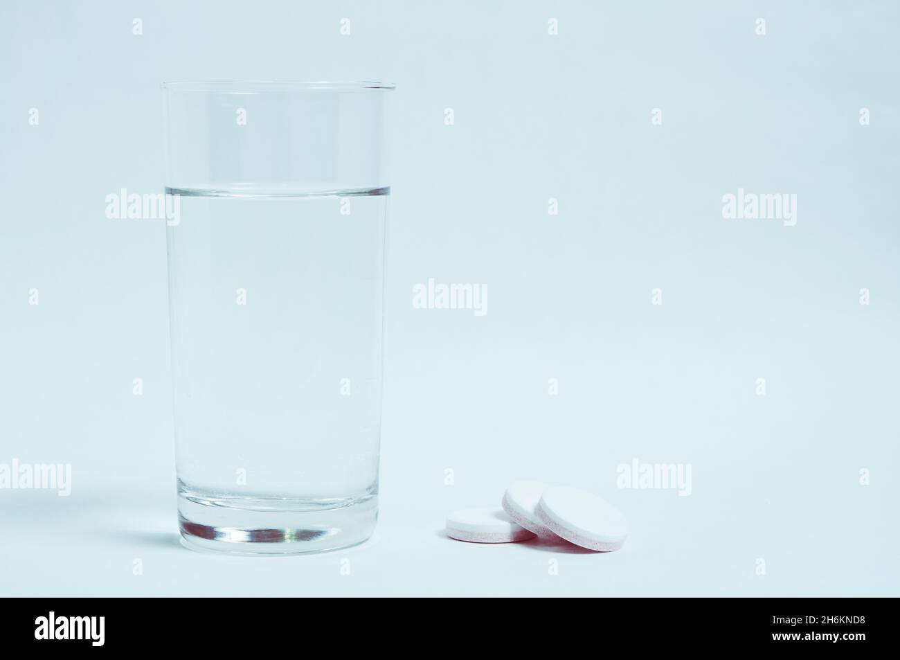 Verre d'eau propre et des pilules sur fond gris Banque D'Images