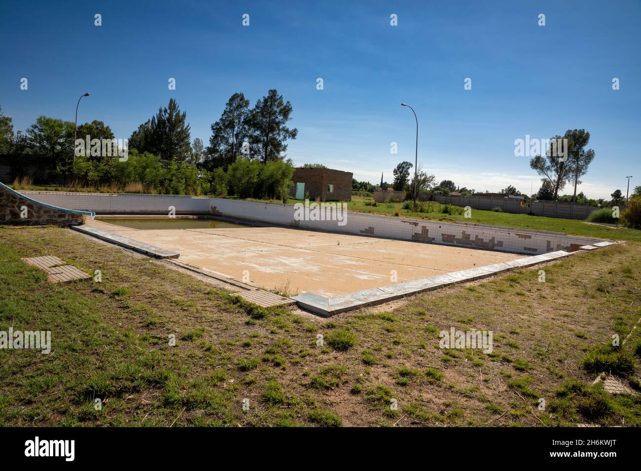 Piscine abandonnée avec un vieux bâtiment derrière elle Banque D'Images