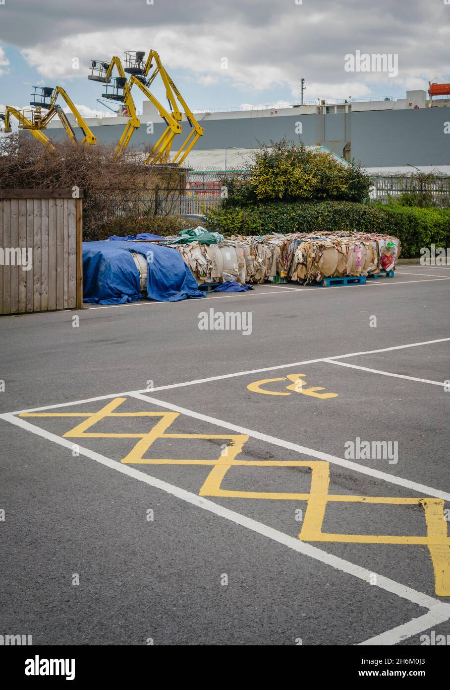 Recyclage du papier emballé dans un parking dans une zone industrielle avec des cueilleurs de cerises en arrière-plan et parking handicapés Banque D'Images