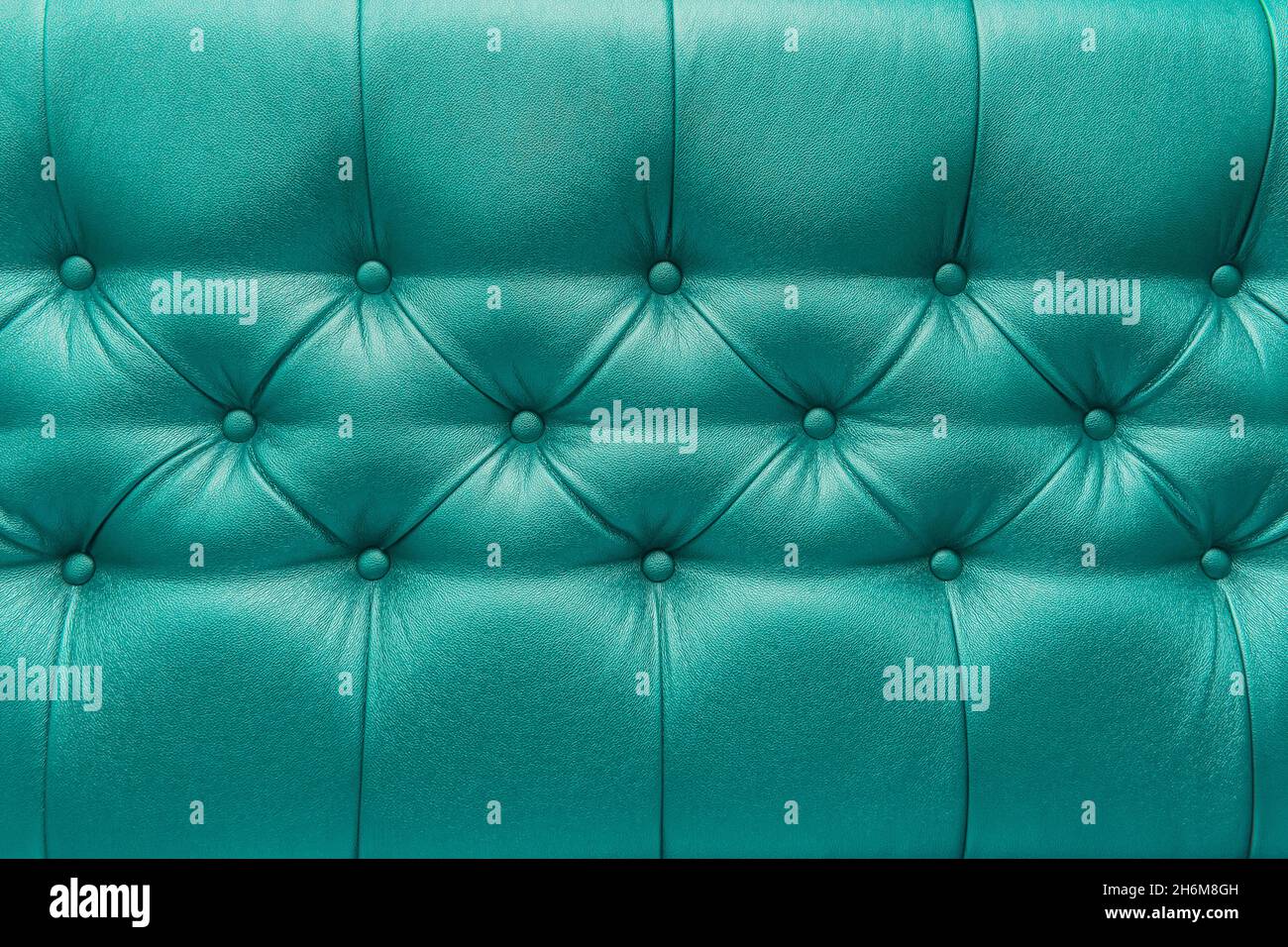 Coussin en cuir vert ou bleu-vert sofa avec motif bouton design mobilier style décor texture fond. Banque D'Images